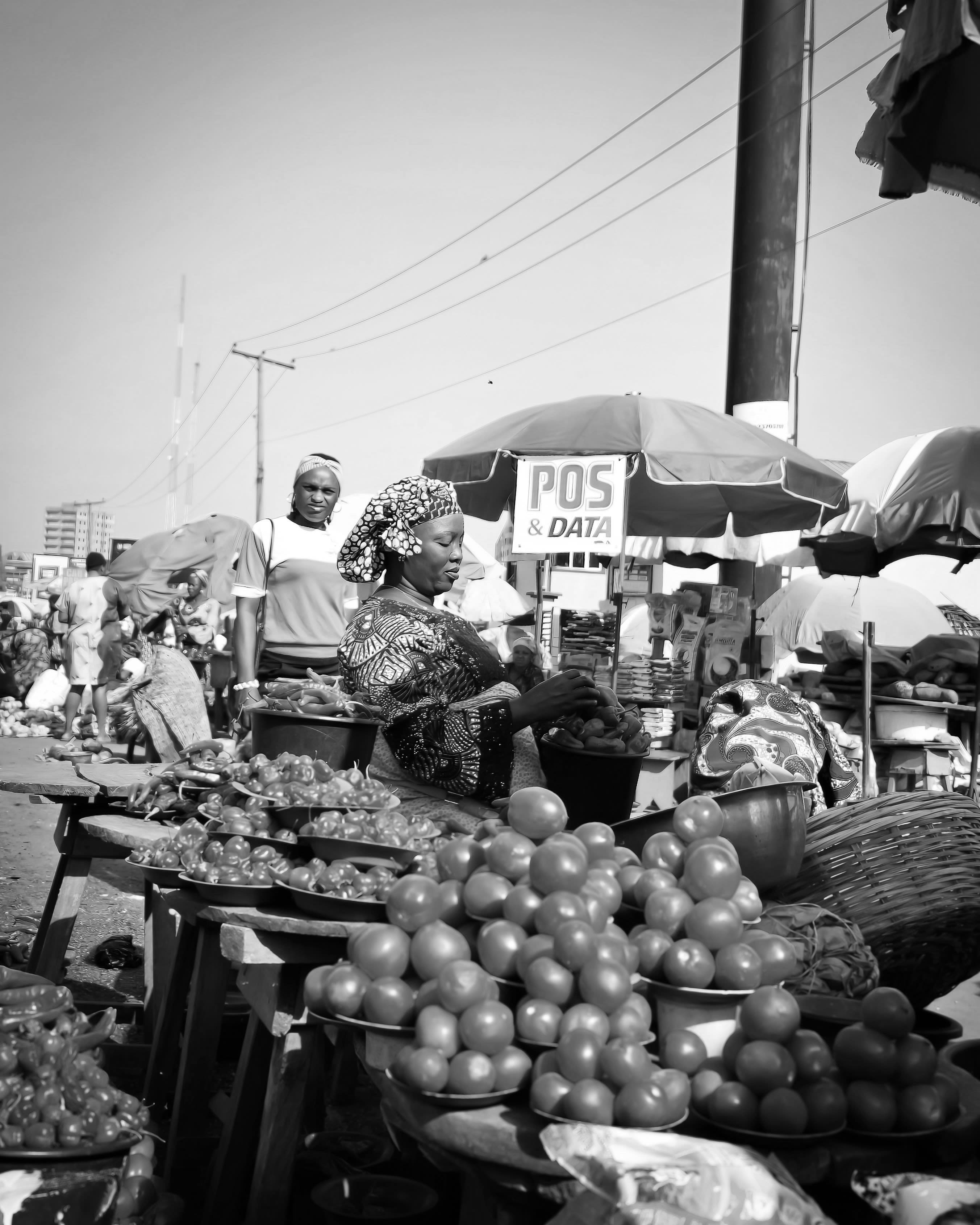 A black woman is selling fresh produce at a street market