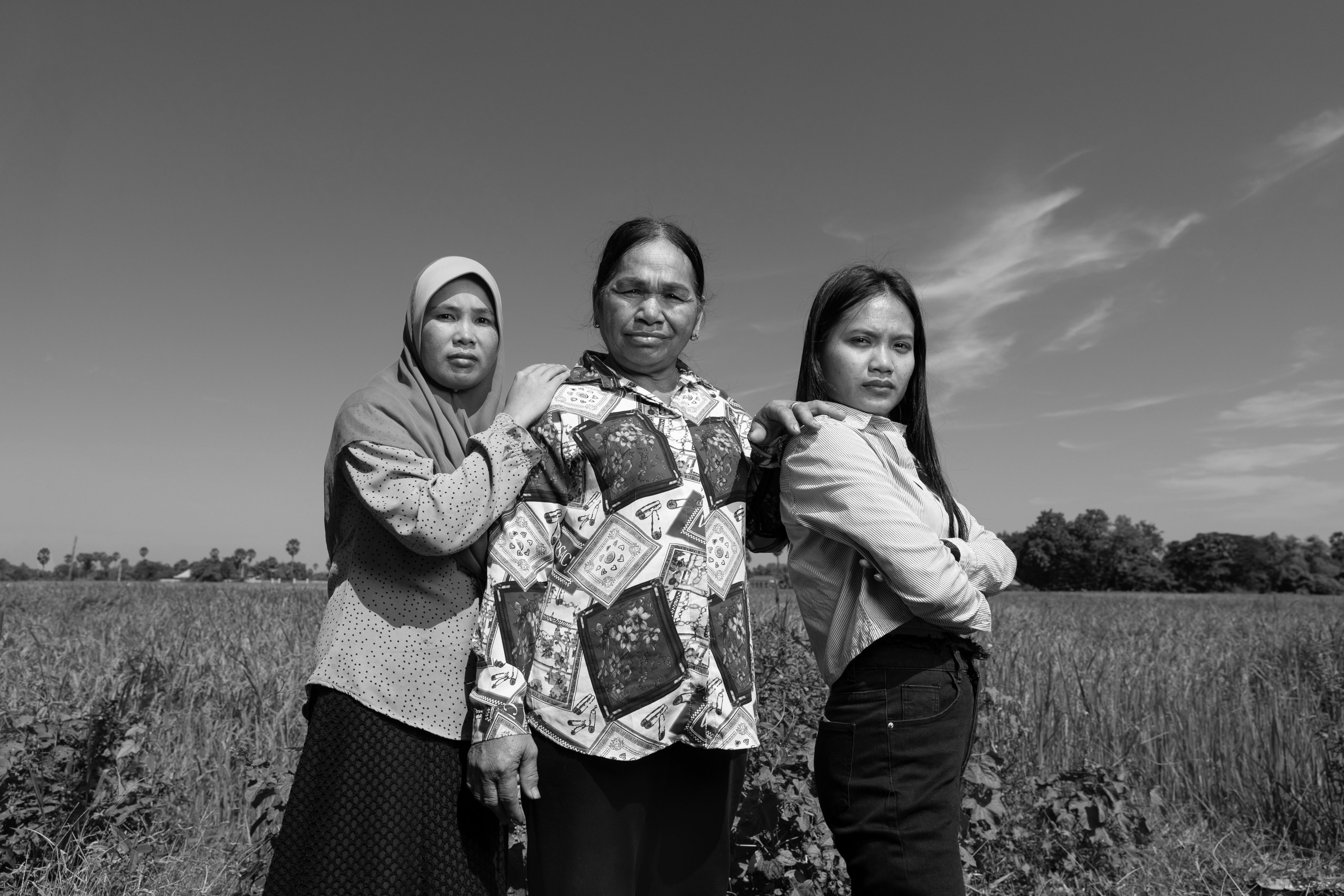 Three Cambodian women stand in a field looking strong