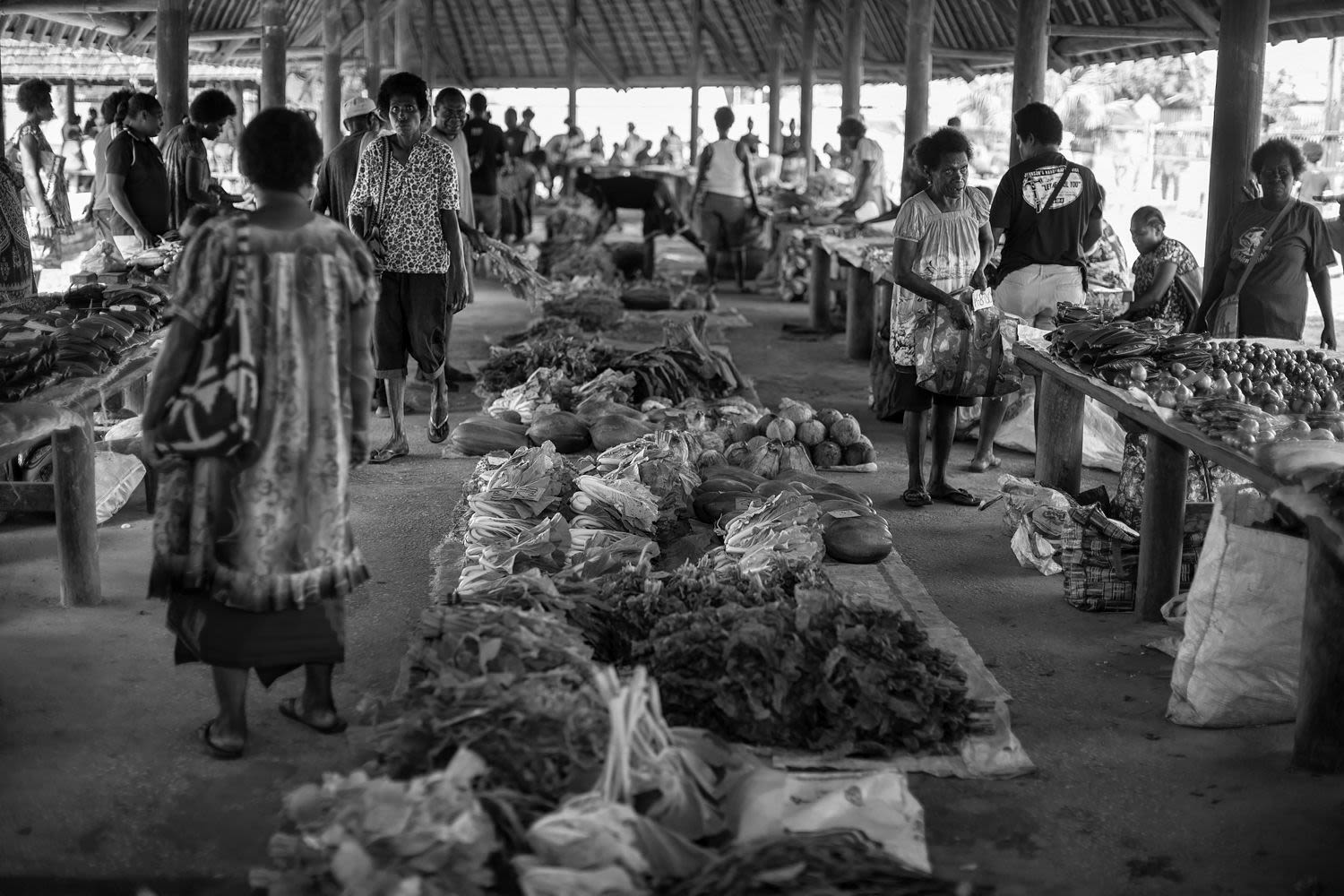 An outdoor produce market in the Pacific with women buying vegetables