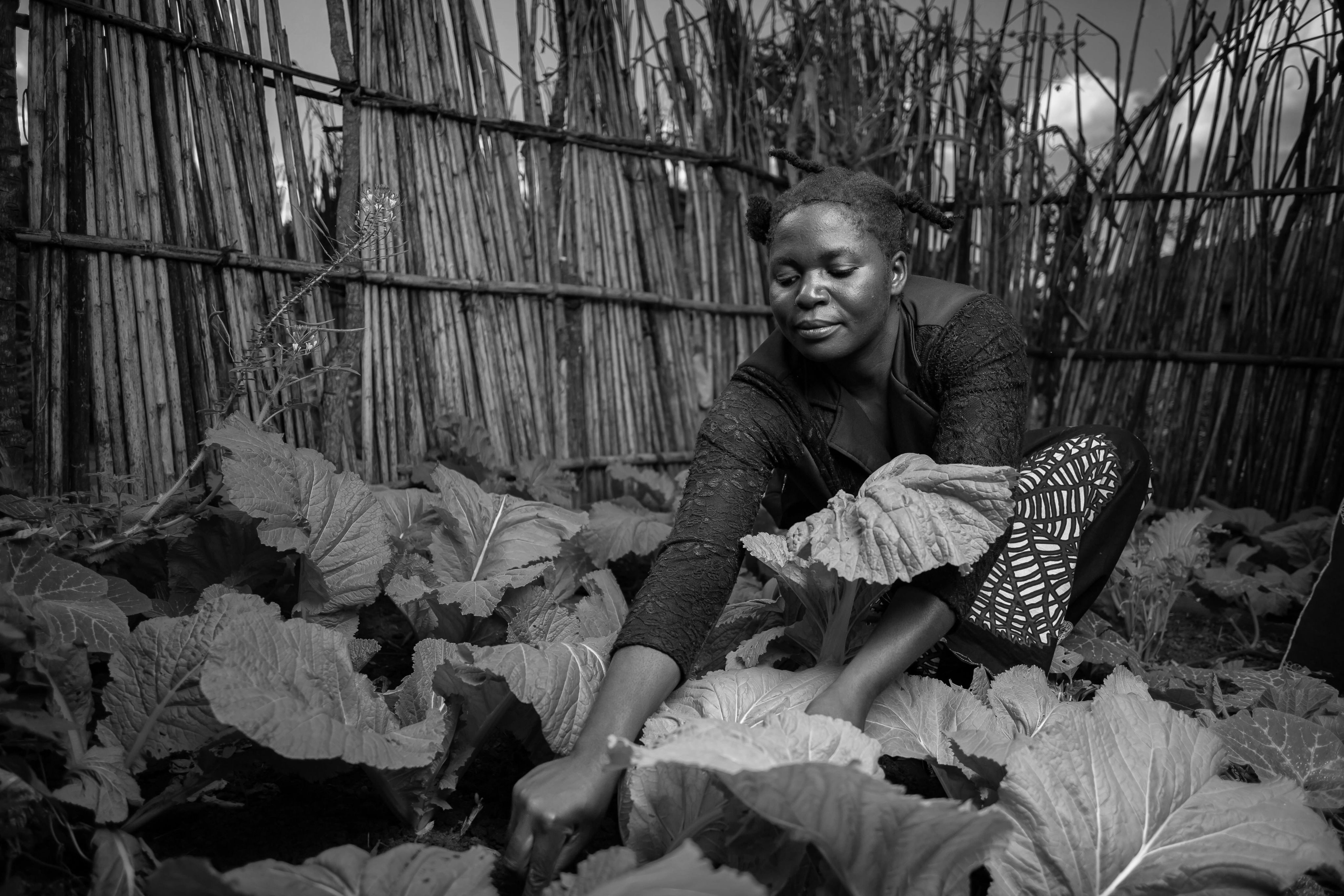 A Black woman tends to her garden growing food