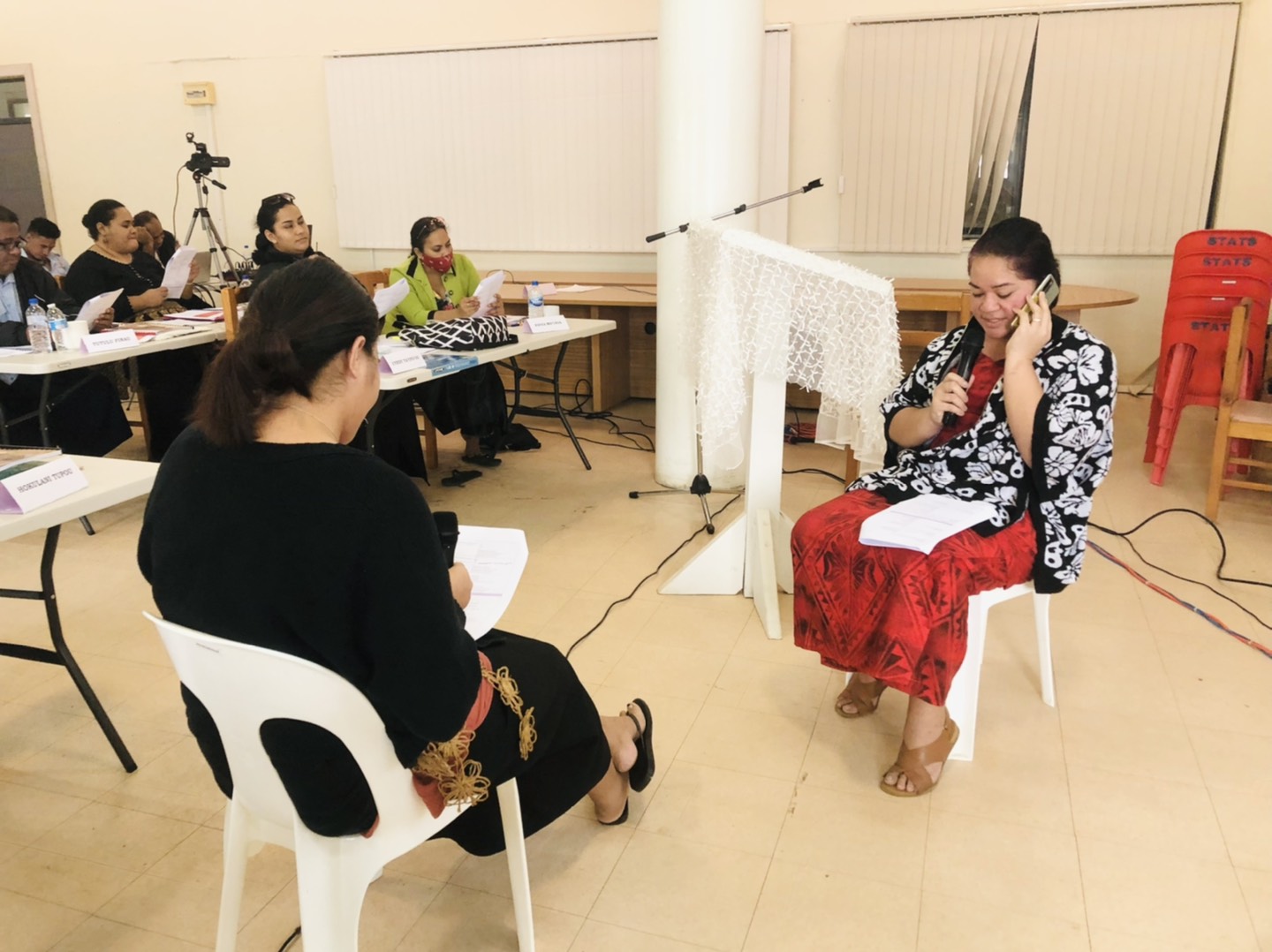 Two women sitting in chairs and practicing delivering and answer the survey