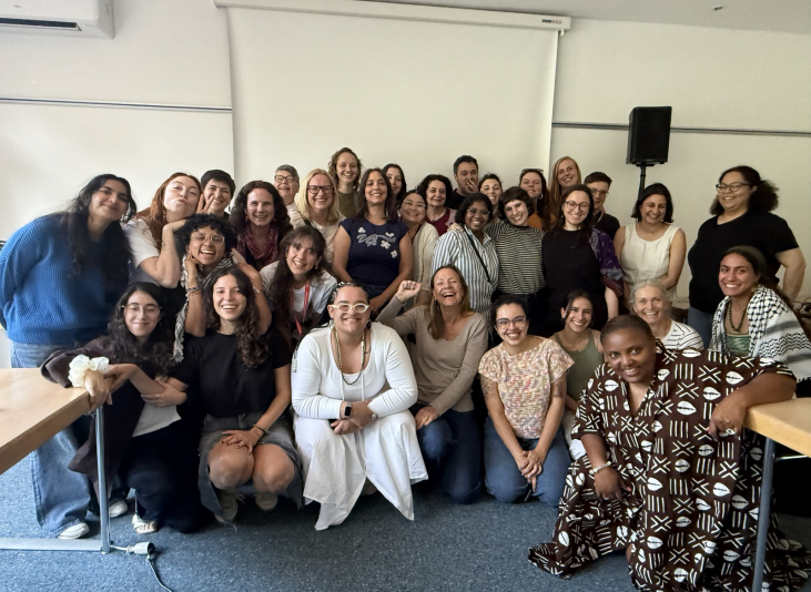 Large group of around 30 diverse people posing and smiling