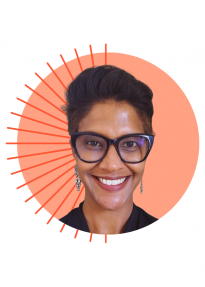 Smiling woman with short black hair and glasses, dangling earrings, in front of an orange circle with sunburst lines.