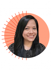 Portrait of a smiling woman with long dark hair, wearing a black polka-dot top, against an orange circular background.